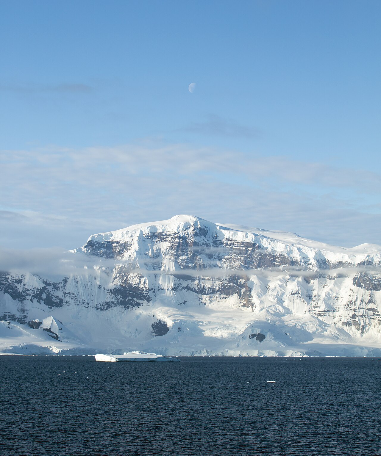 Falaises et étendues glacées de la péninsule Antarctique, au bord d’une mer sombre.